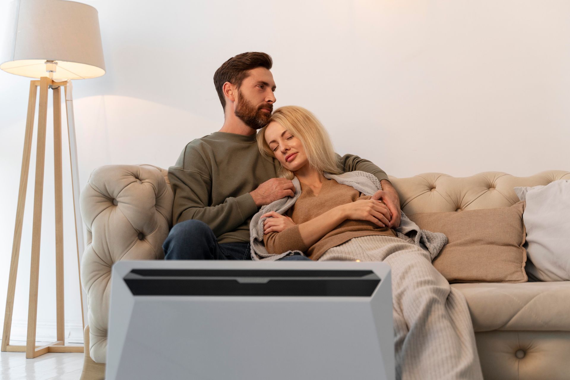 A man and a woman are sitting on a couch in front of a television.