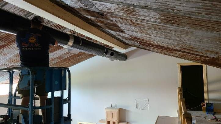 A man is standing on a lift working on the ceiling of a room.