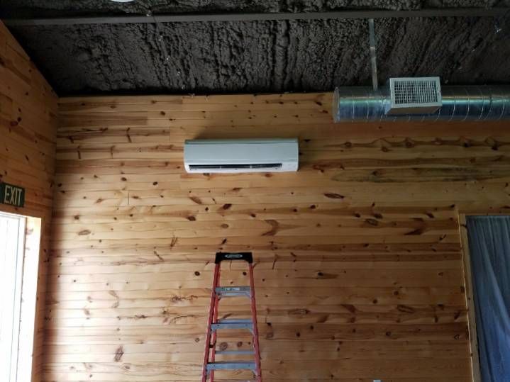 Two air conditioners are sitting on the side of a brick building.