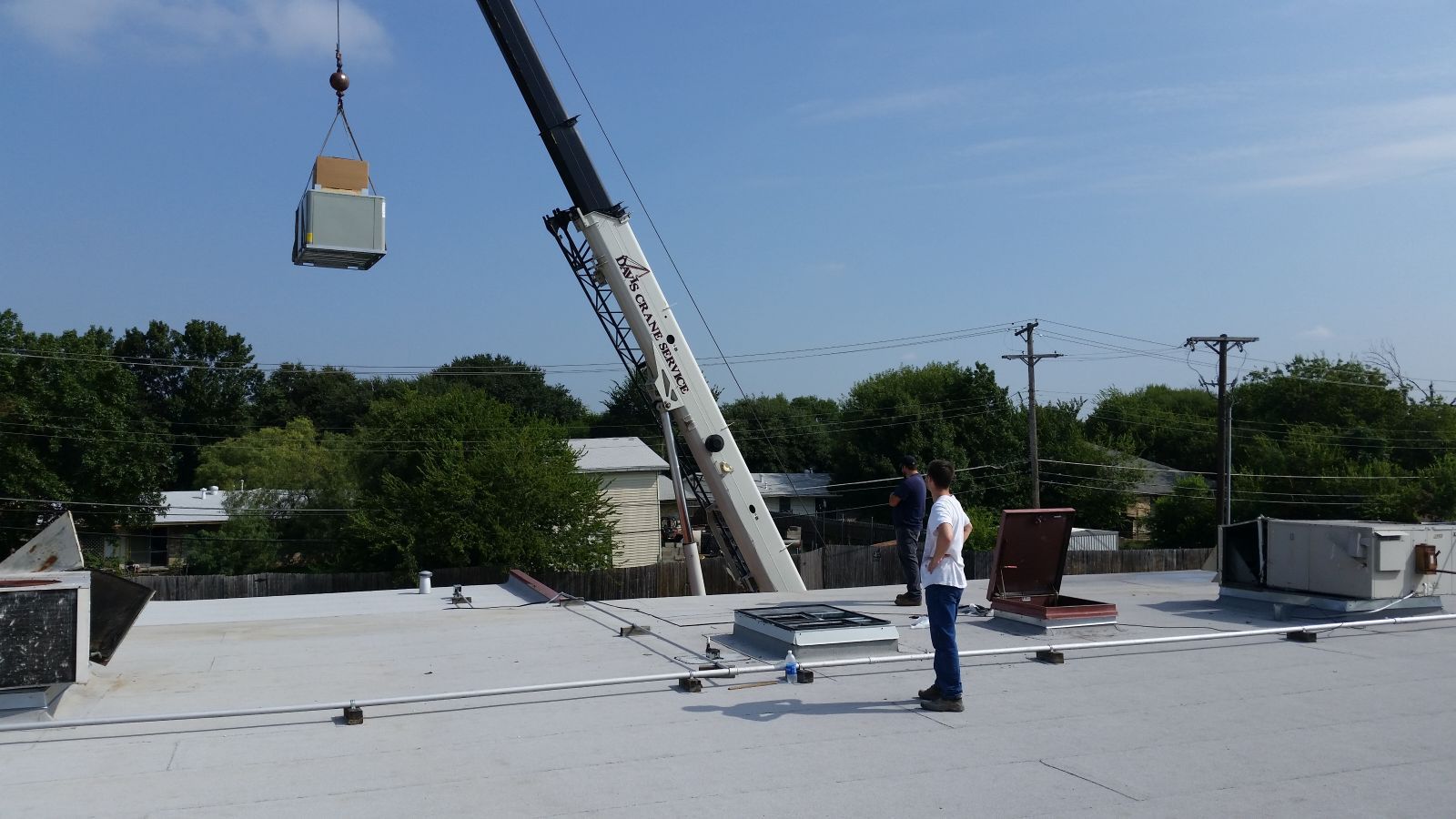 Two air conditioners are sitting in the grass in front of a brick building.