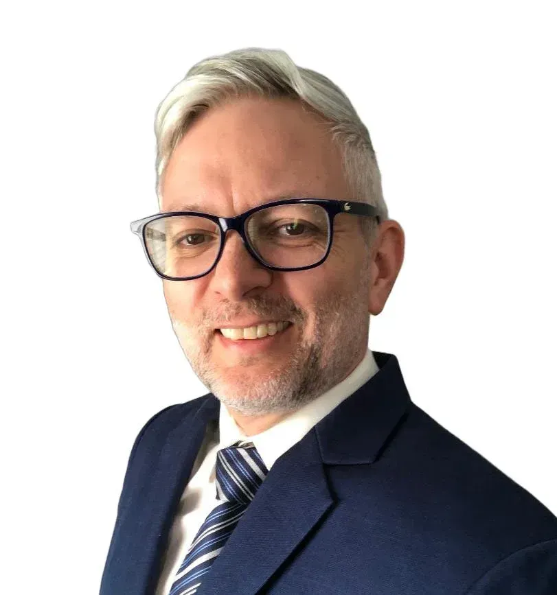 Man with glasses, smiling in a blue suit and tie.