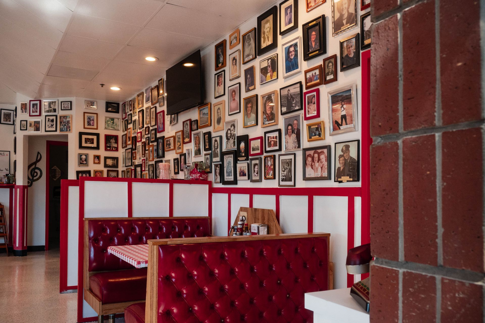 Red upholstered booths in a photo-filled restaurant interior with white and red walls