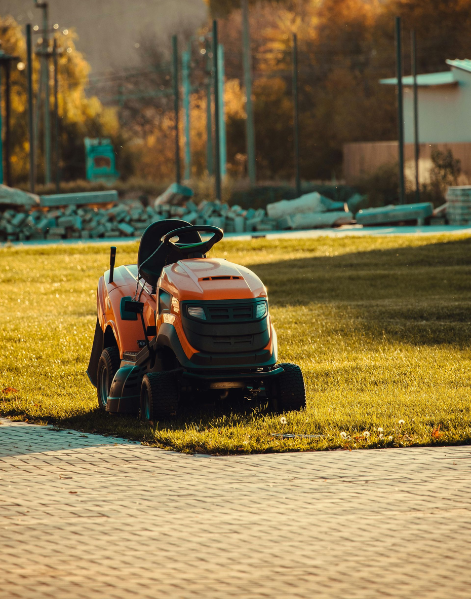 Green John Deere riding lawnmower with a yellow seat and wheels. Other lawnmowers are visible in the background.
