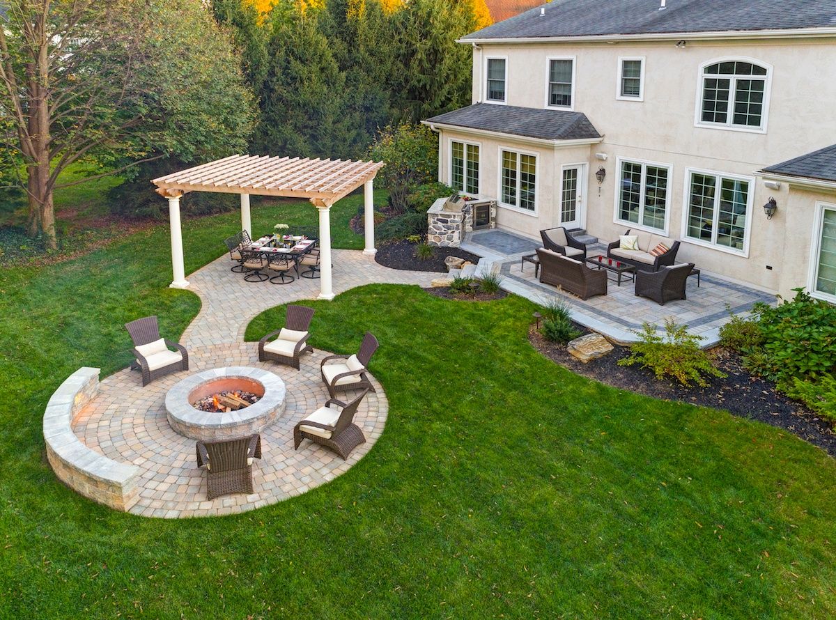 An inviting outdoor space featuring a beautifully designed paver patio adorned with a pergola, a cozy fire pit, and a fully equipped outdoor kitchen.