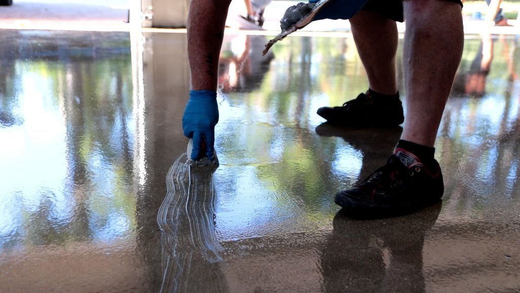 An epoxy resin contractor ensuring epoxy resin evenness across a concrete floor.