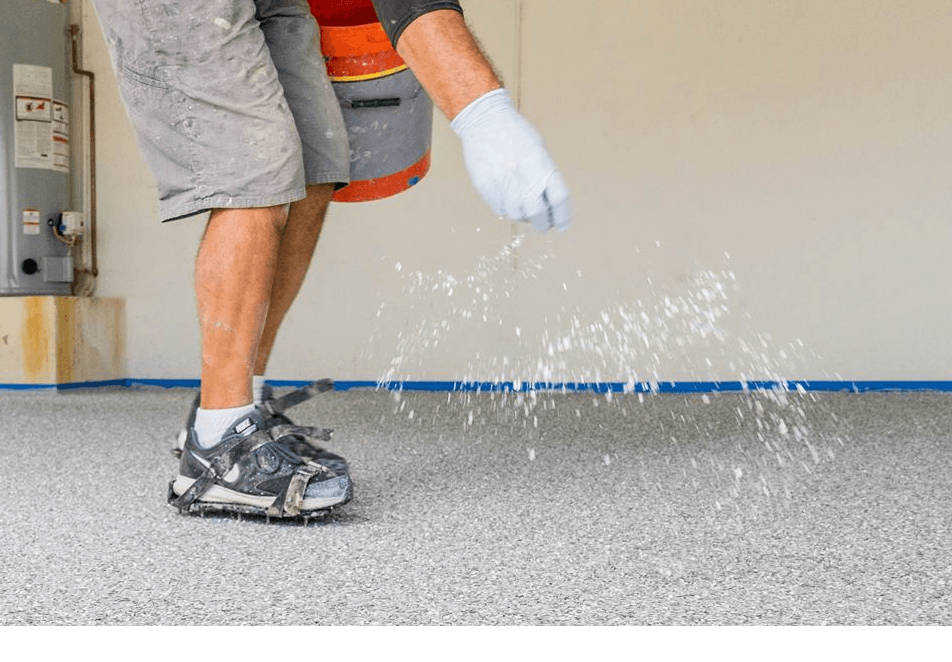 A man is pouring water on a concrete floor in a garage.