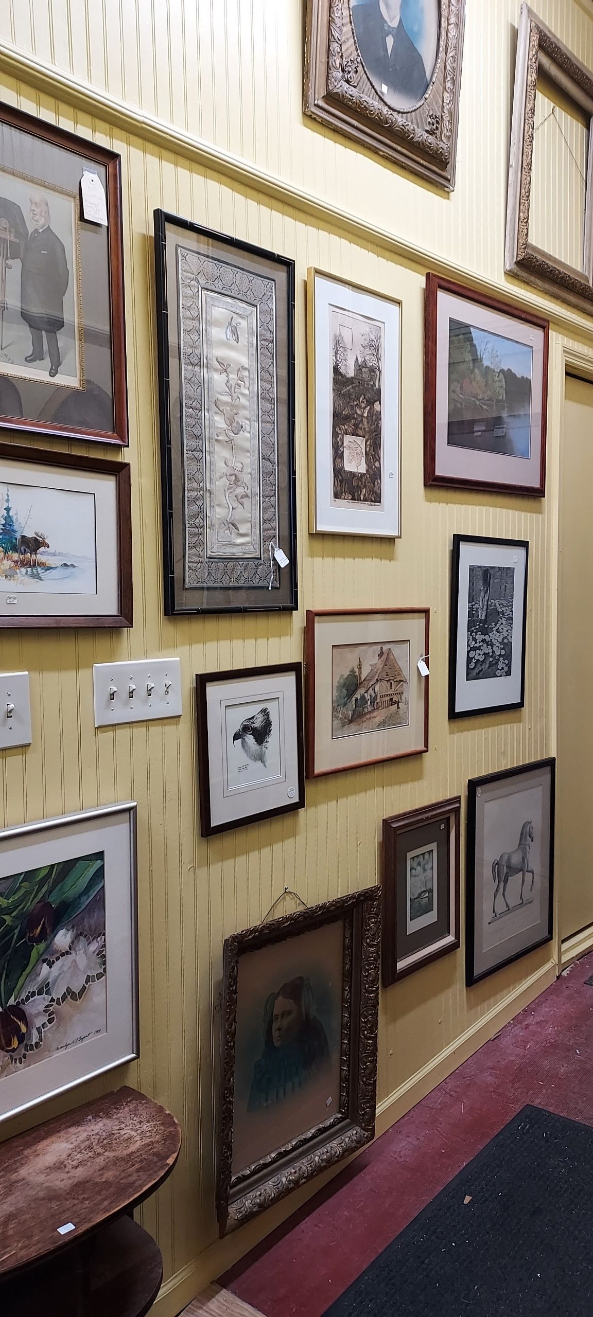 A group of paintings are hanging on a wall in a museum.