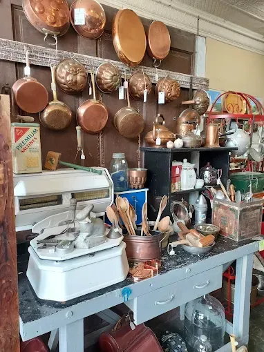 A room filled with lots of copper pots and pans hanging on the wall.