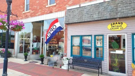 A red white and blue flag is hanging outside of a store.