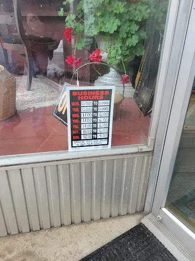 A sign in a store window shows the hours of operation.