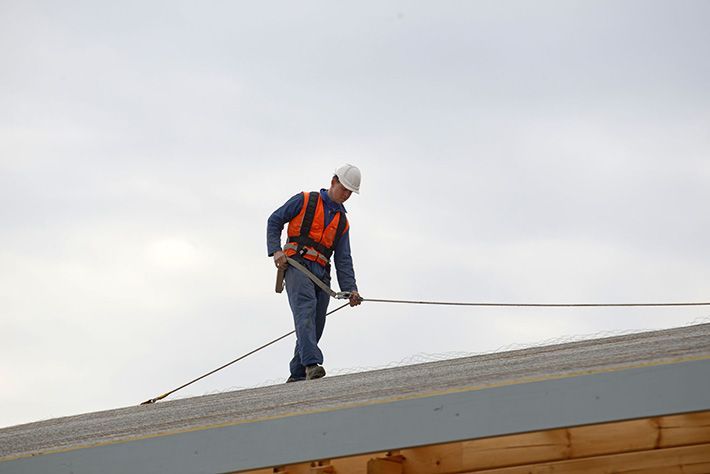 A man is standing on top of a roof holding a rope.