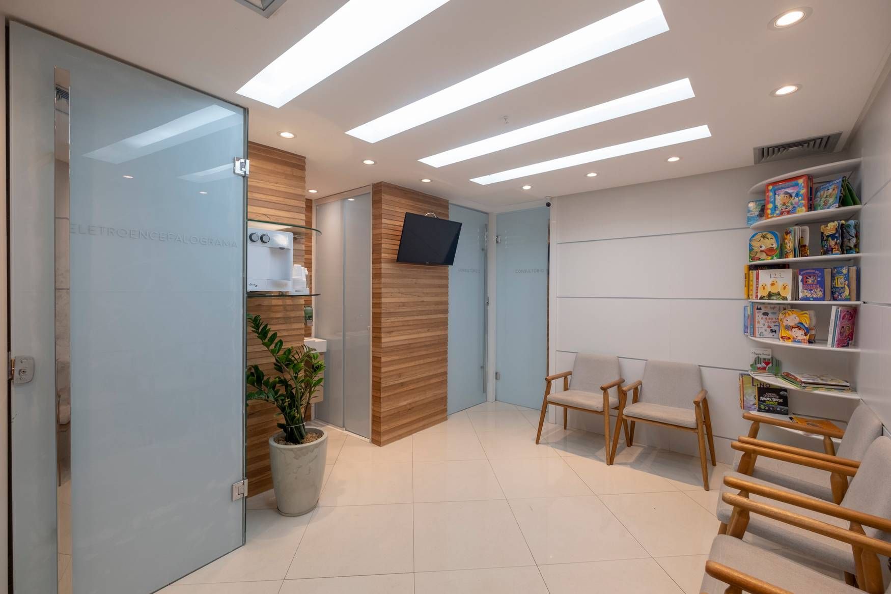 Uma sala de espera com cadeiras e uma TV na parede.