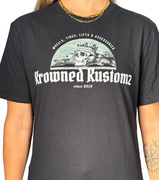 A woman is wearing a crowned kustomz t-shirt