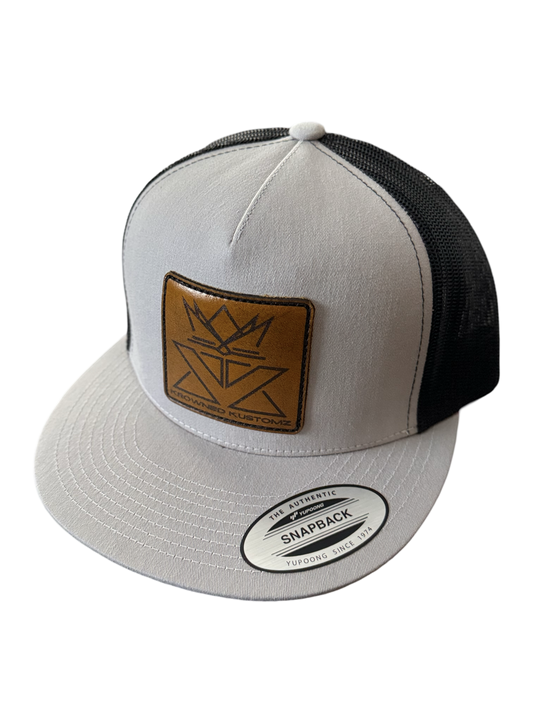 A white and black hat with a brown leather patch on it.