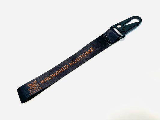 A black keychain with the words crowned kustomz on it.
