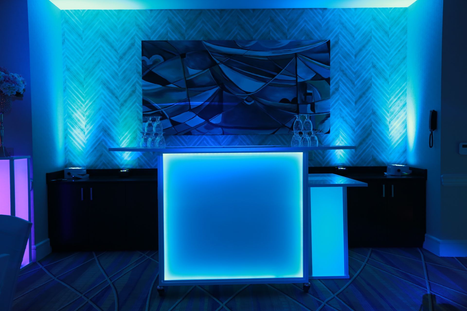 A bar is lit up with blue lights in a room.