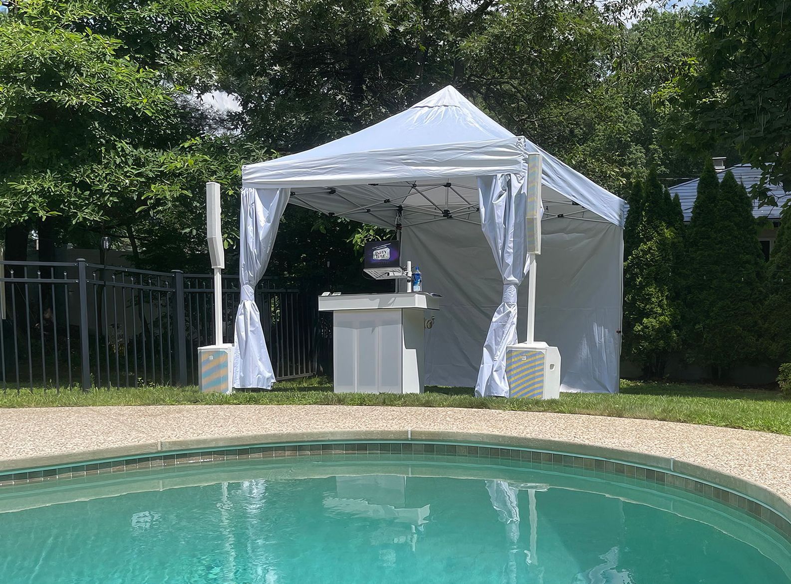 A white tent is sitting next to a swimming pool.