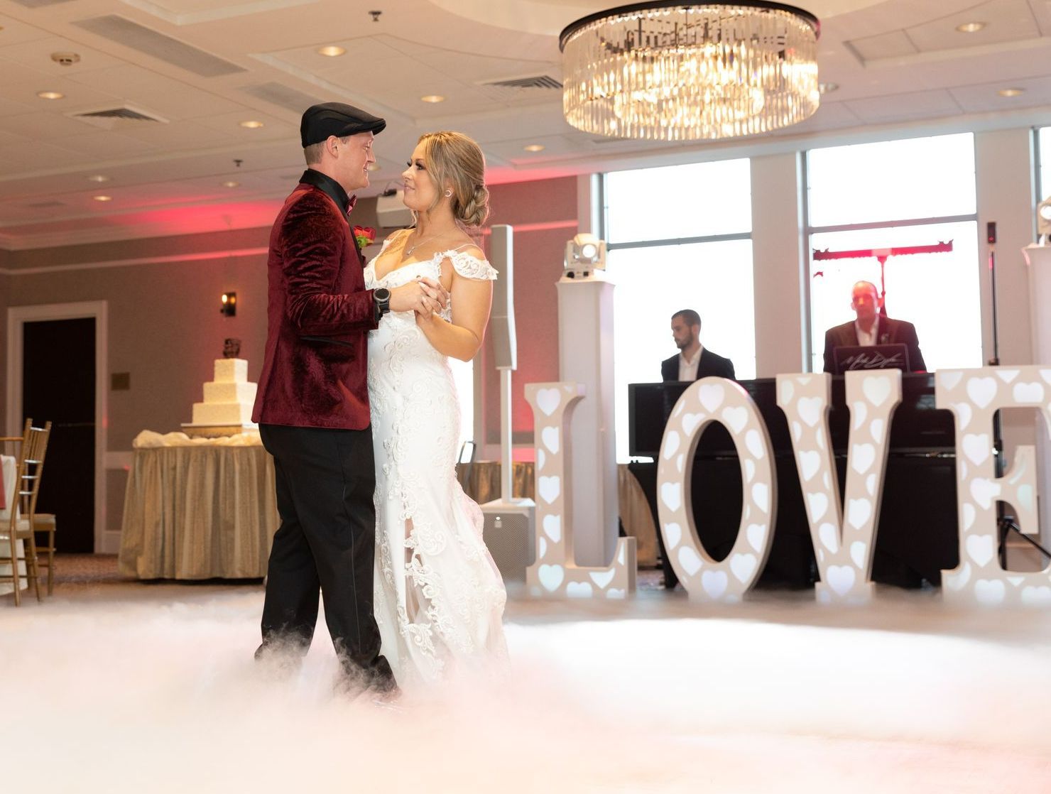 A bride and groom are dancing in front of a love sign.