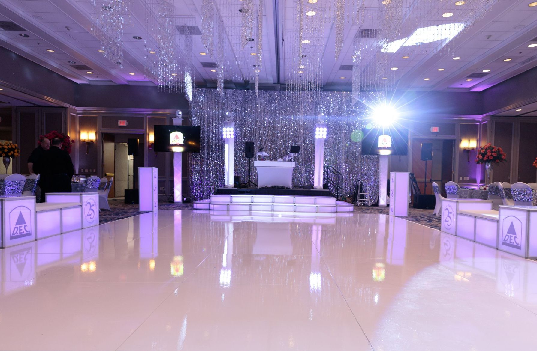 A large room with a white dance floor and a dj.