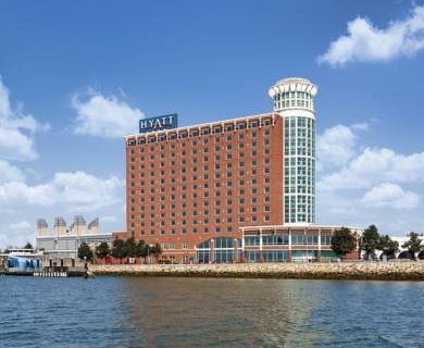 A large brick building with the word hyatt on it is next to a body of water.