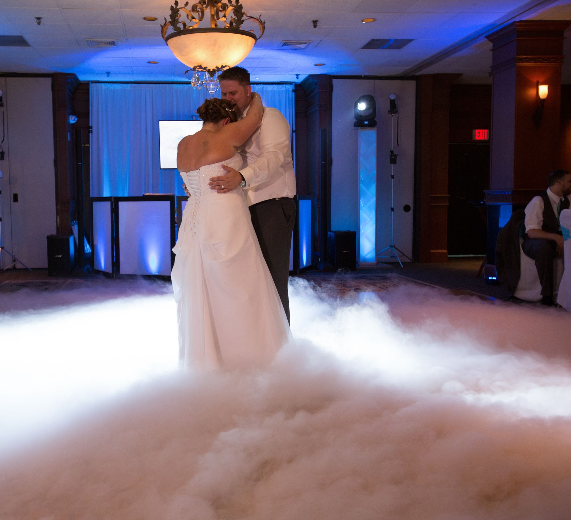 A bride and groom are dancing in a room filled with smoke