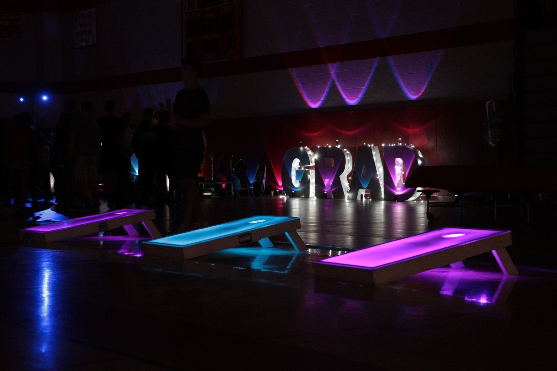 A group of cornhole boards are lit up in a dark room.