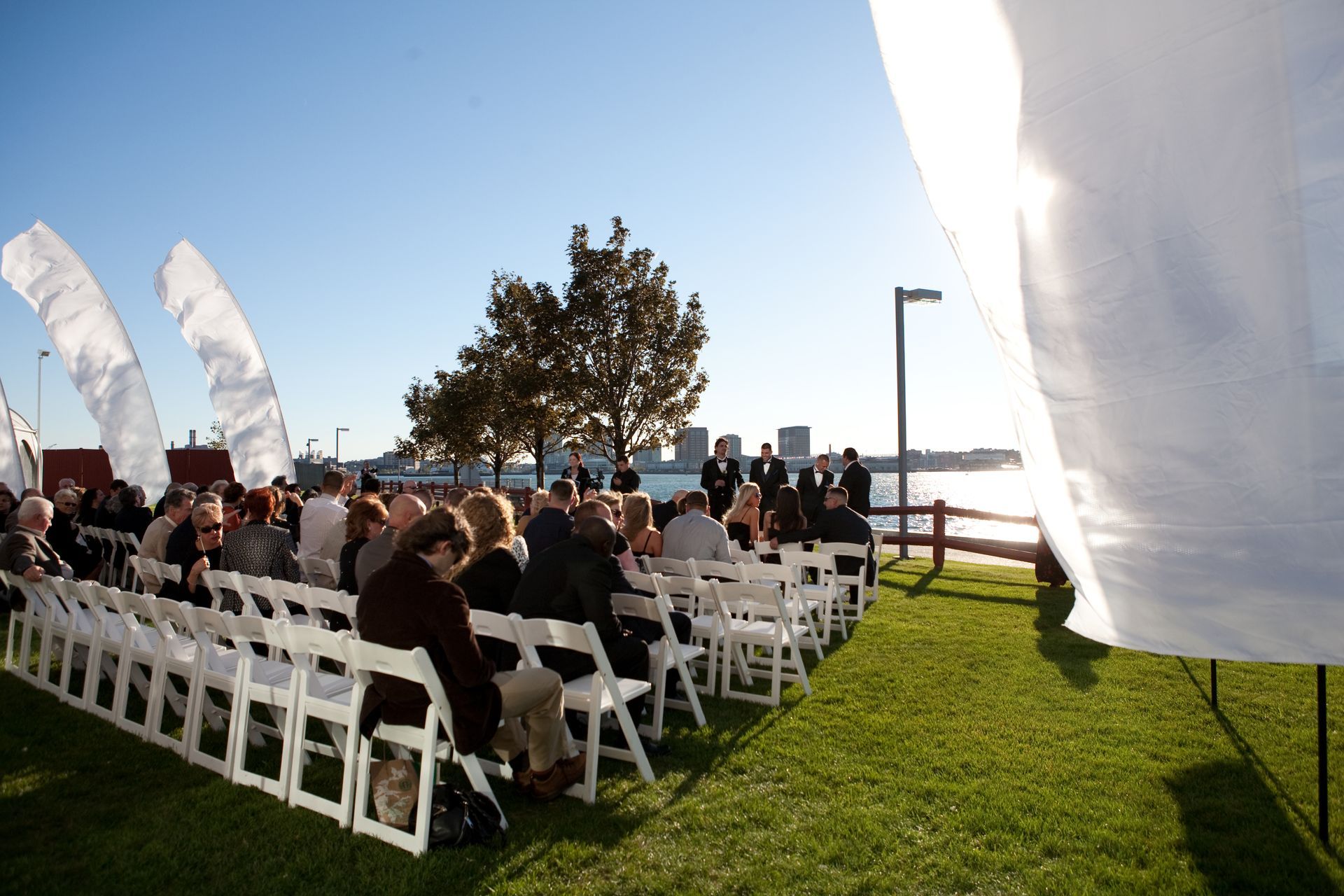 A group of people sitting in white chairs in a field