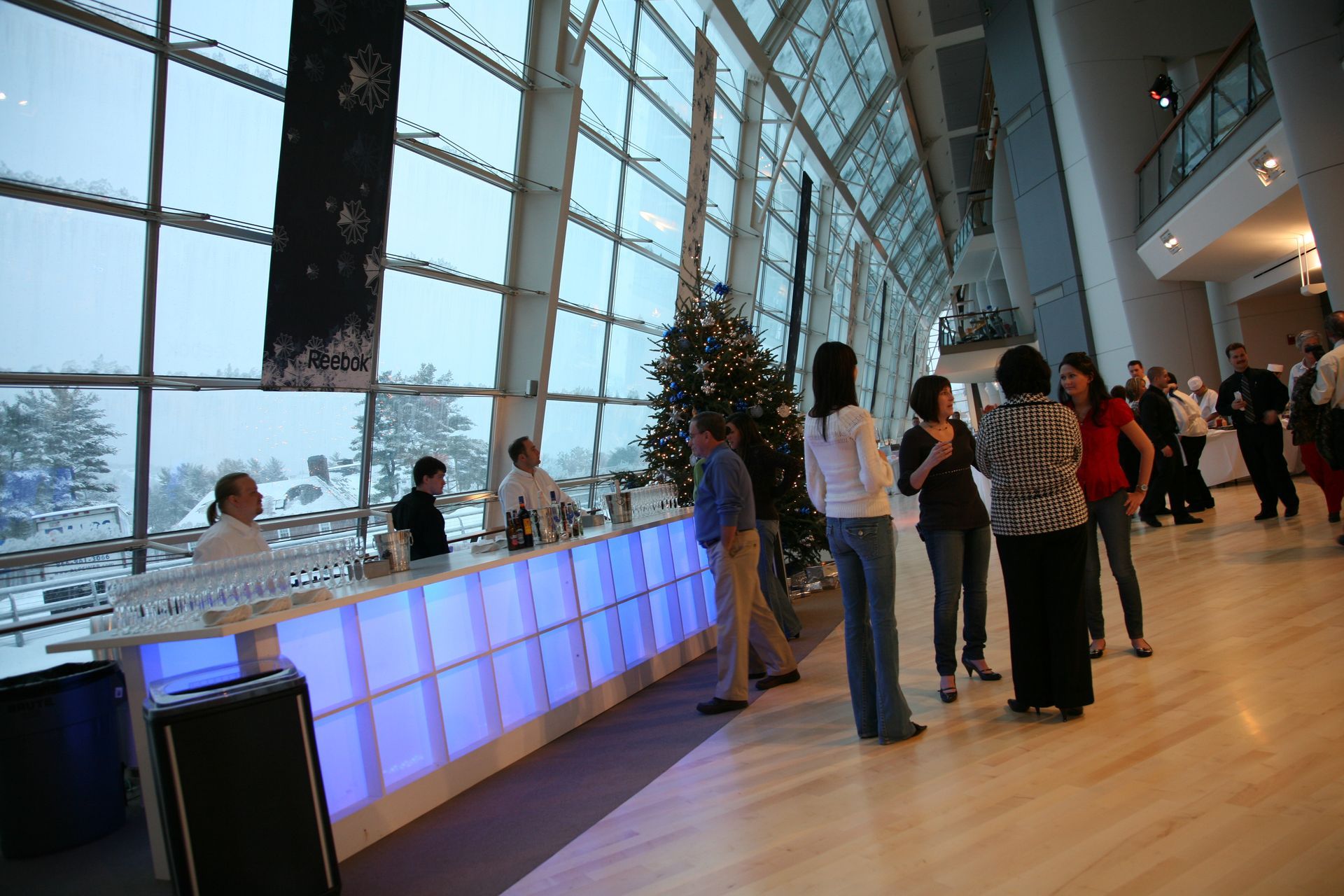 A group of people are standing around a bar in a large building