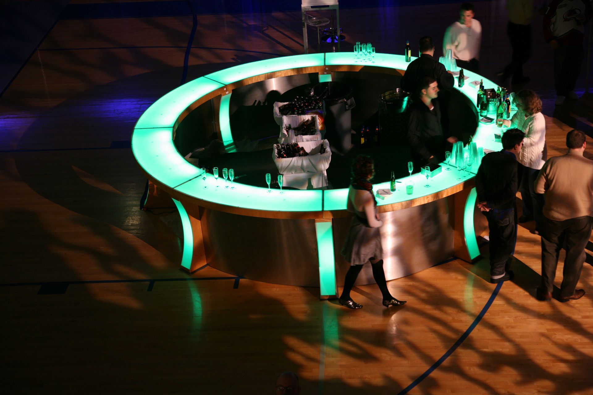 A group of people standing around a circular bar with green lights