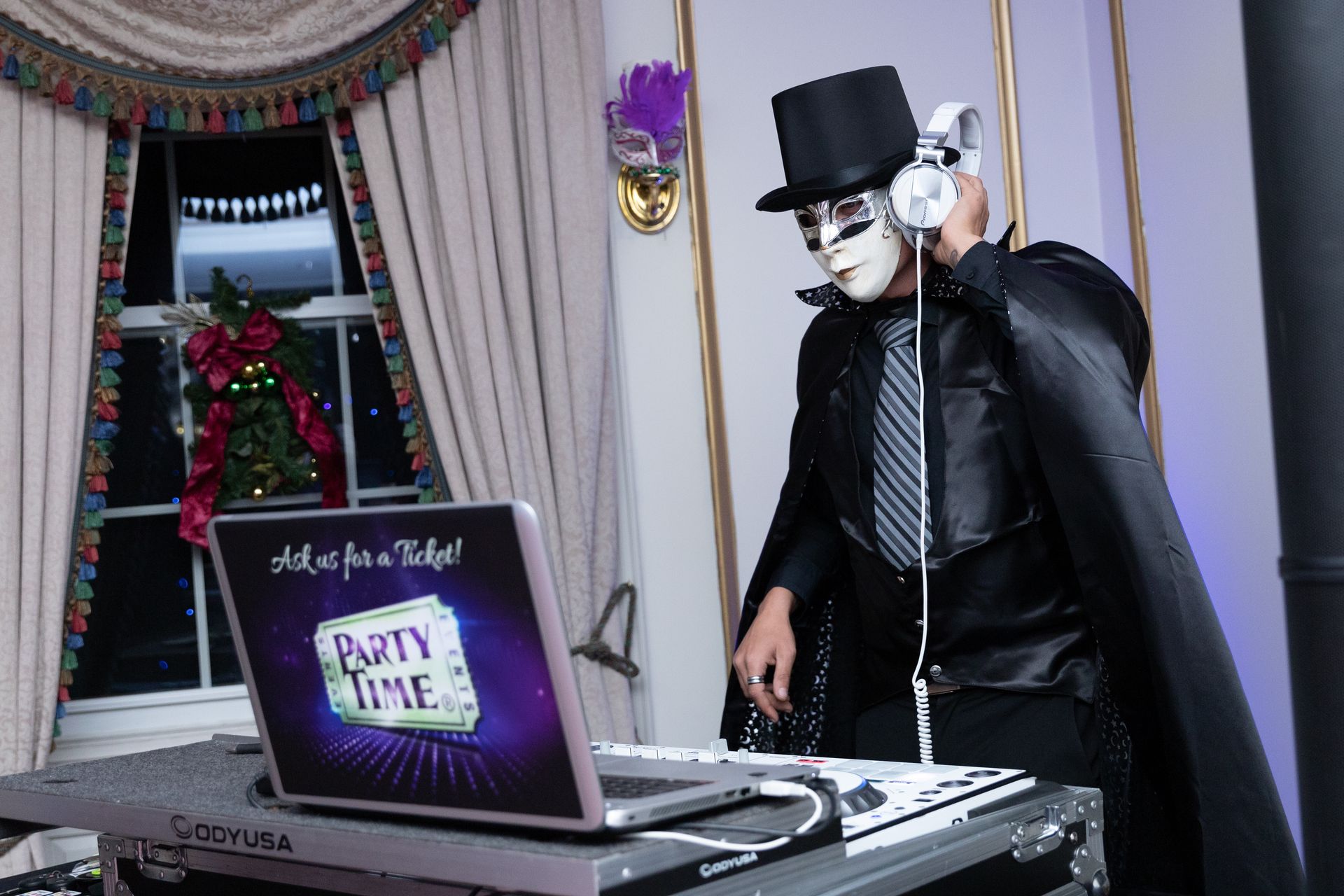 A man in a mask is standing in front of a laptop that says party time