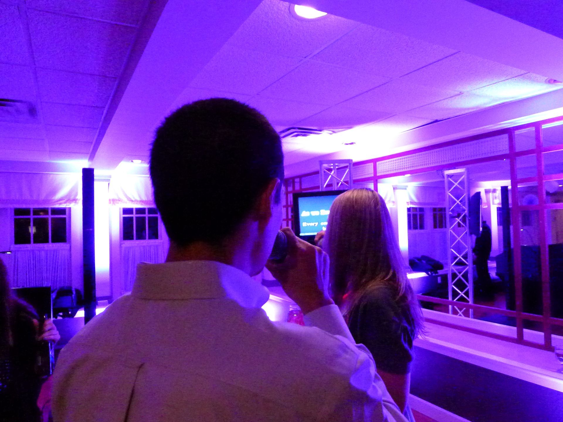 A man and woman are standing in a room with purple lights