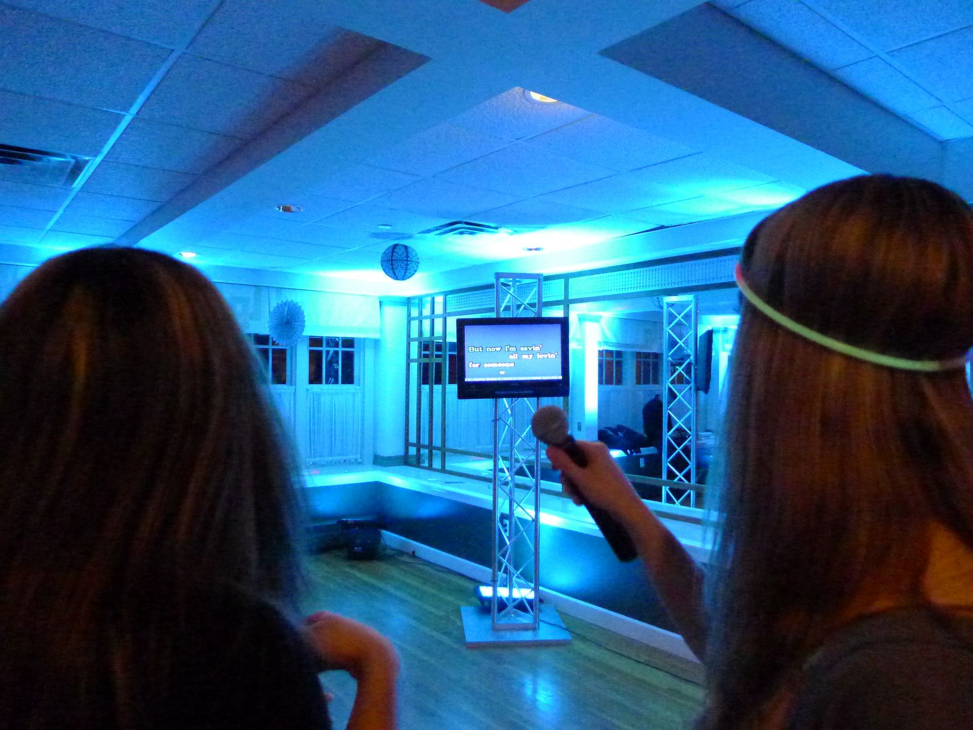 A woman is holding a microphone in front of a television