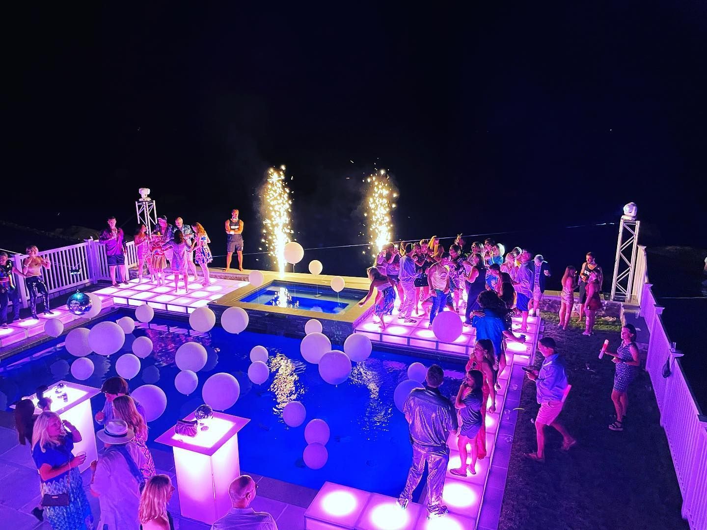 A group of people are dancing in a dark room with their hands in the air.