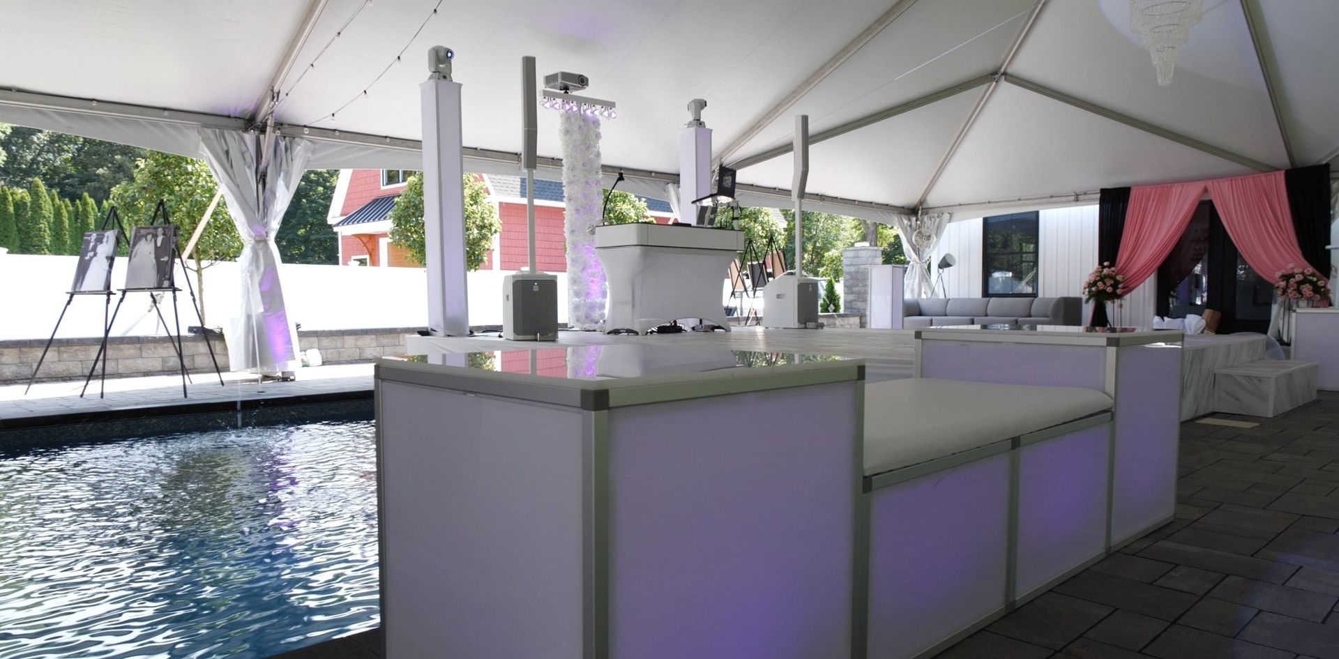 A large tent with tables and a pool in the background.