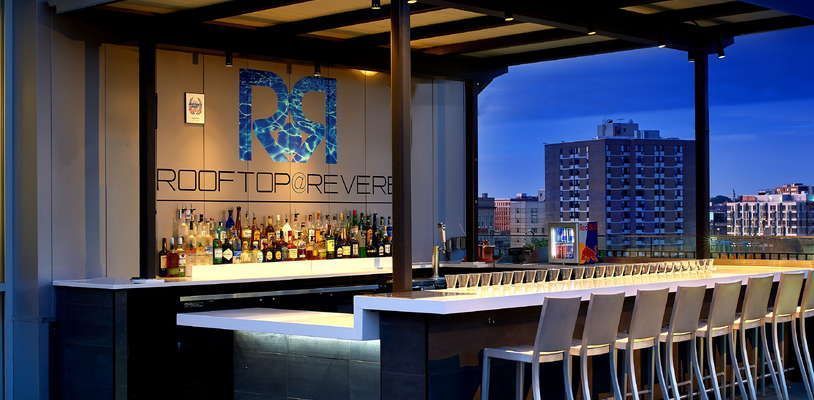 A bar with a lot of stools and a sign that says rooftop reverb.