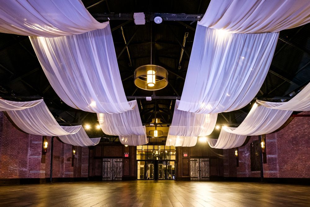 A large empty room with white curtains hanging from the ceiling.