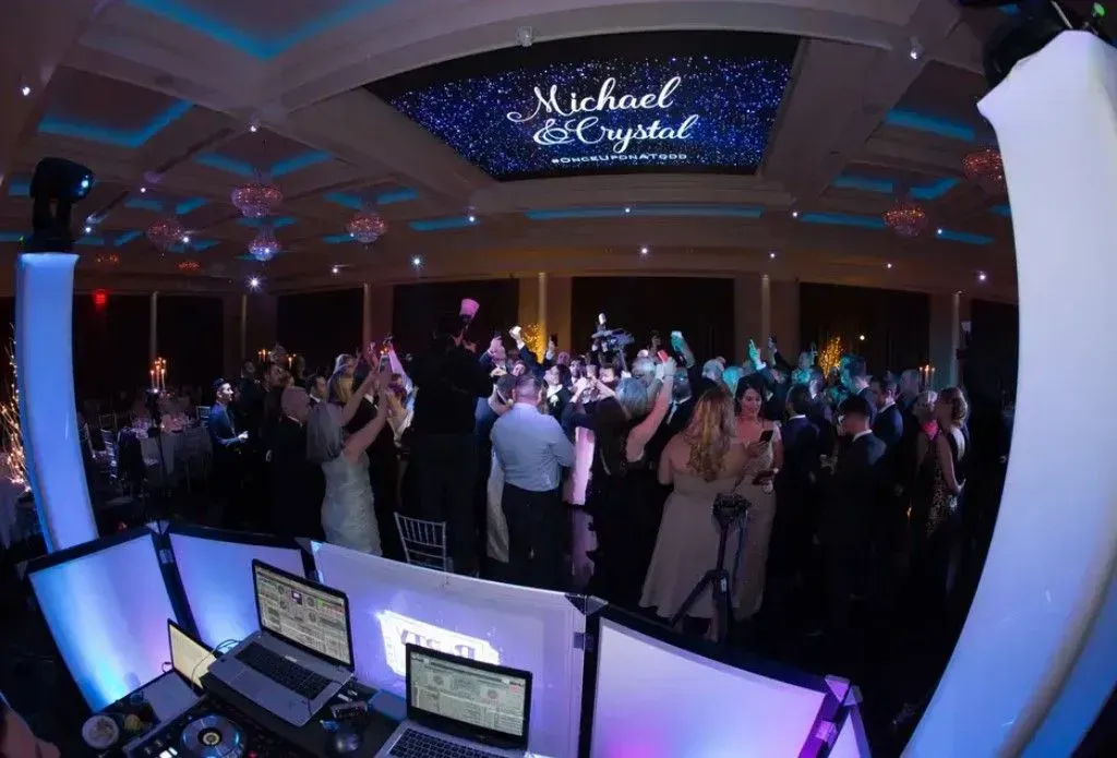 A large group of people are dancing at a wedding reception.