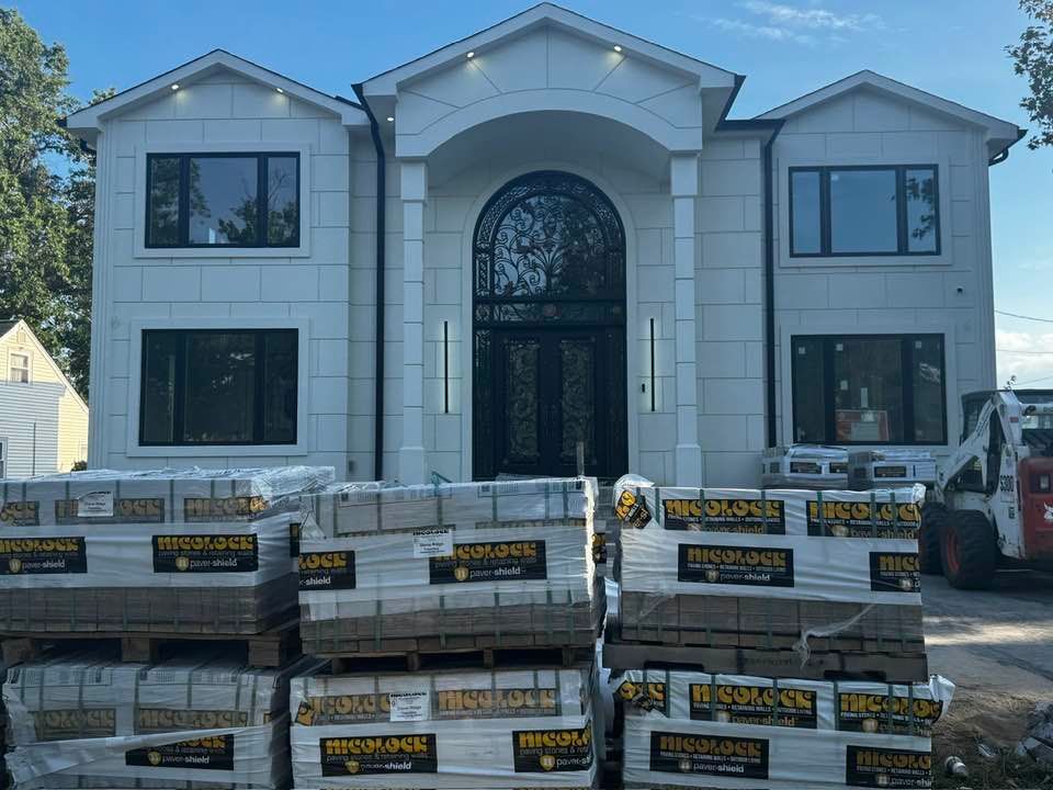 New construction house with stone facade, black windows and door, and construction materials in front.