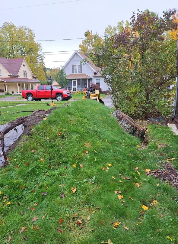 A red truck parked near a grass lawn with construction. Two houses in the background.