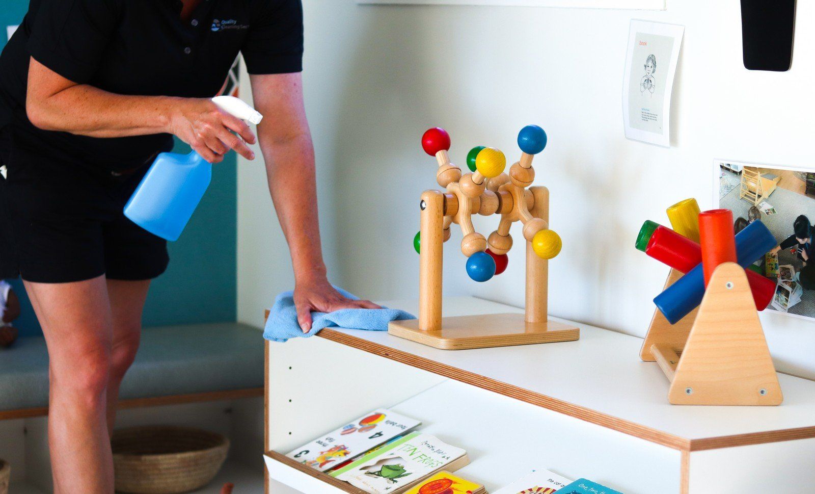 A woman is cleaning a table with a spray bottle.