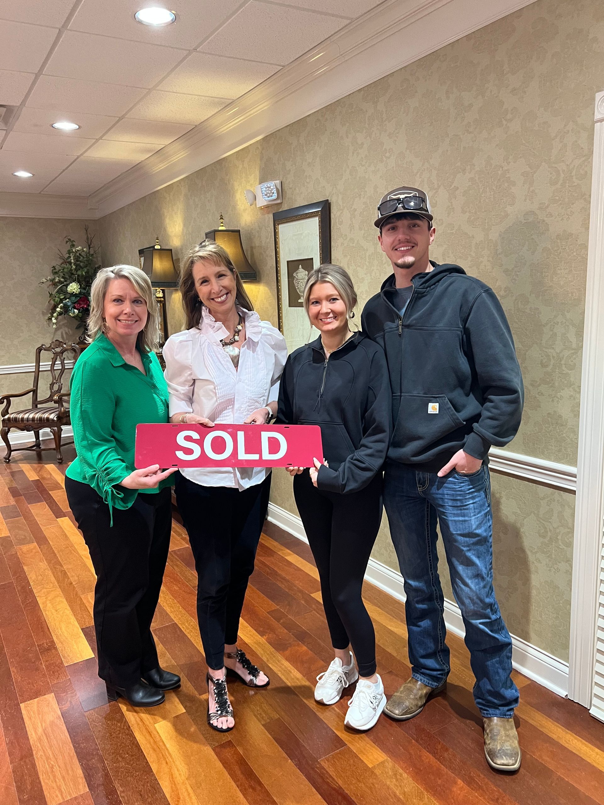 Four people standing in a hallway holding a red 