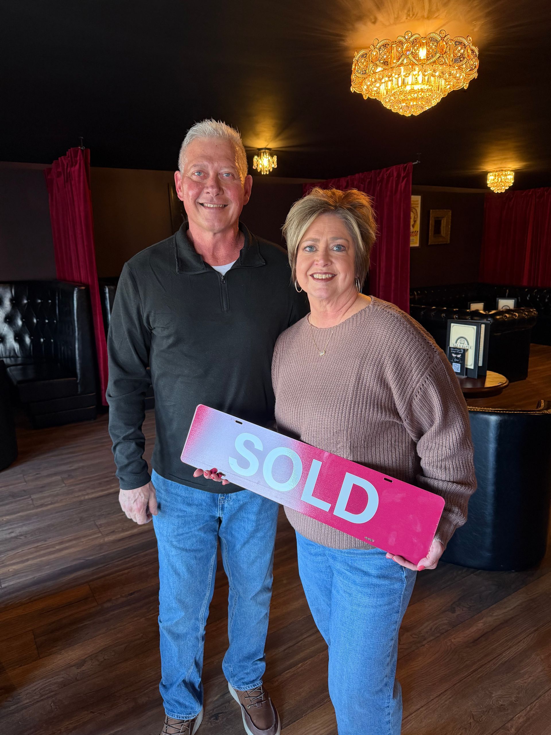 Two people smiling while holding a pink 