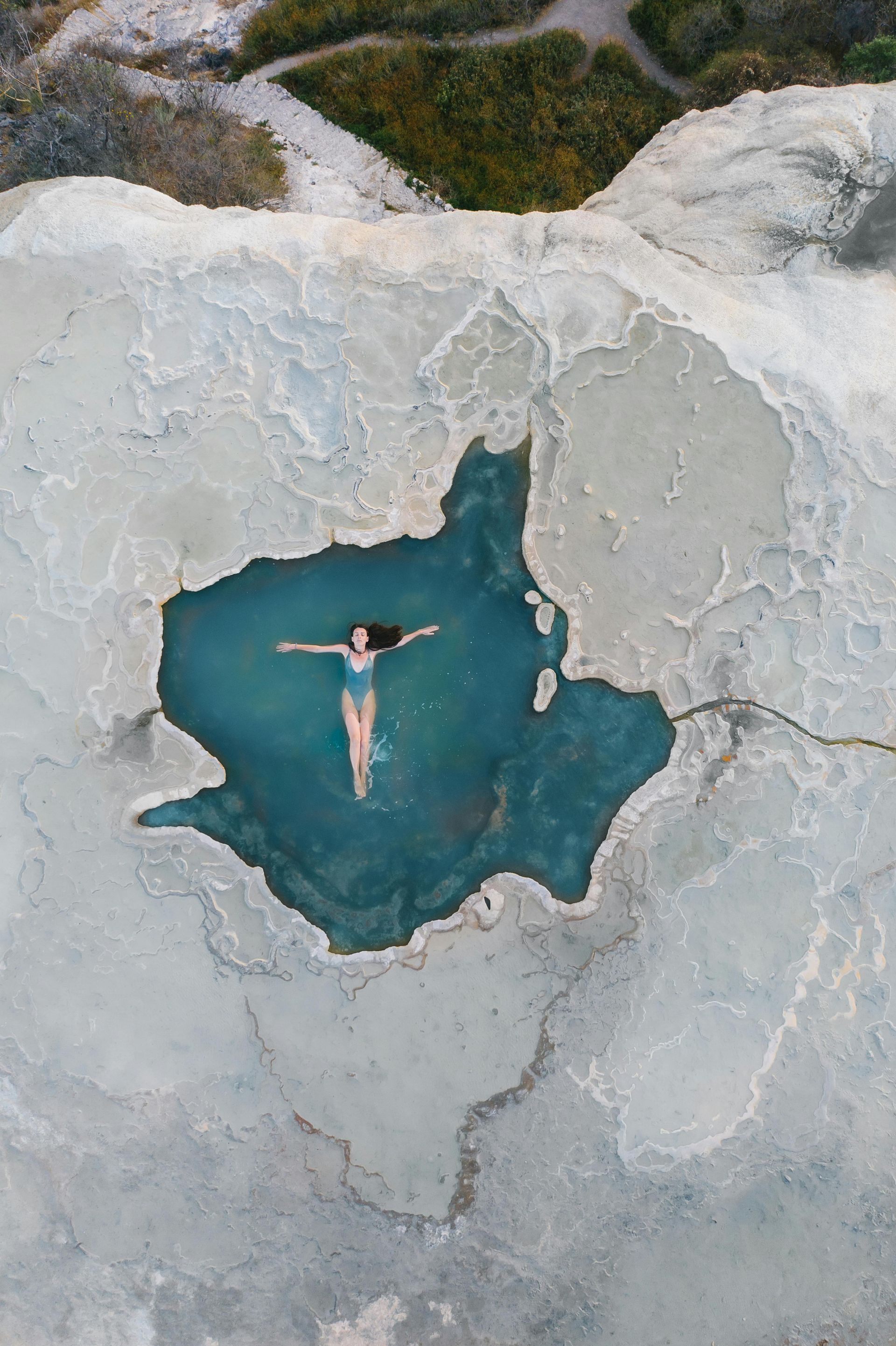 Una vista aérea de una mujer flotando en una piscina de agua.