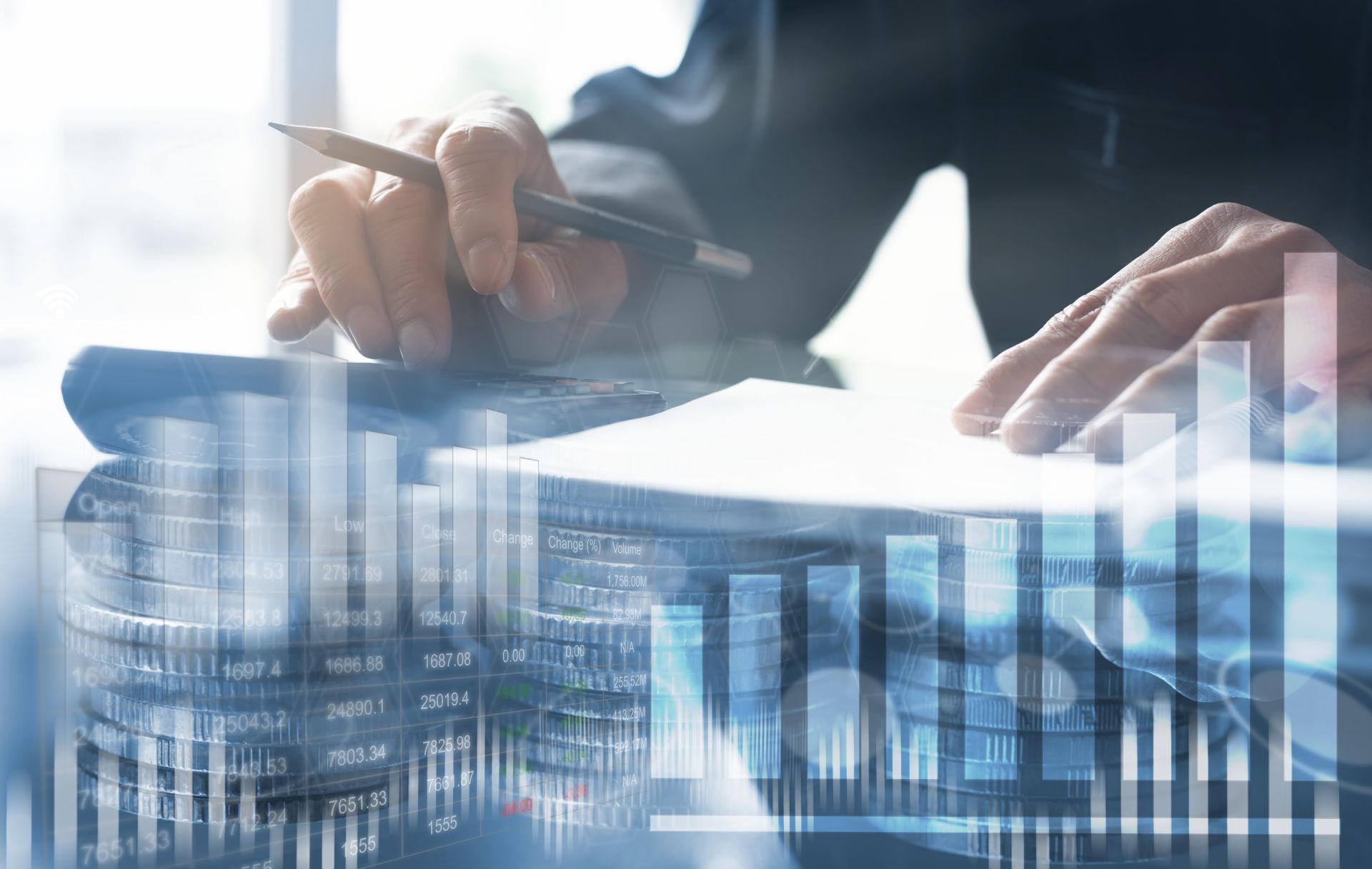 Hands writing on paper, superimposed over graphs and stacked coins, suggesting finance.