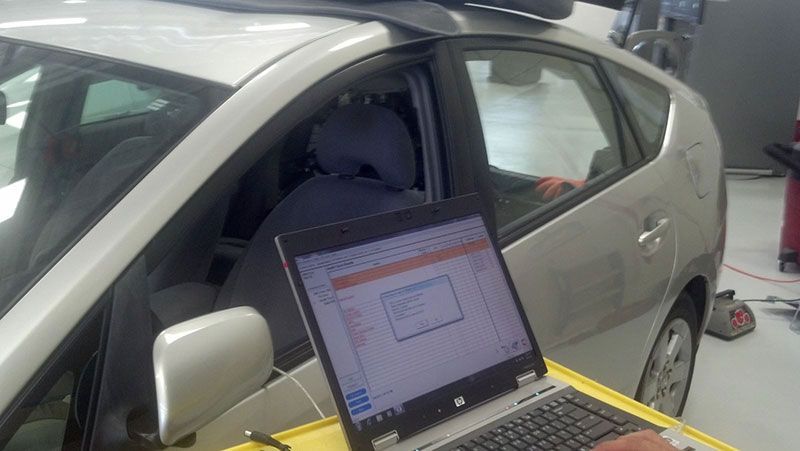 A person is using a laptop in front of a car | Autotrends