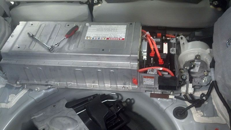 A battery is being removed from a car with a screwdriver | Autotrends