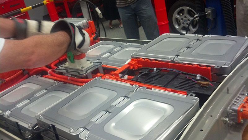 A person is working on a car battery in a garage | Autotrends