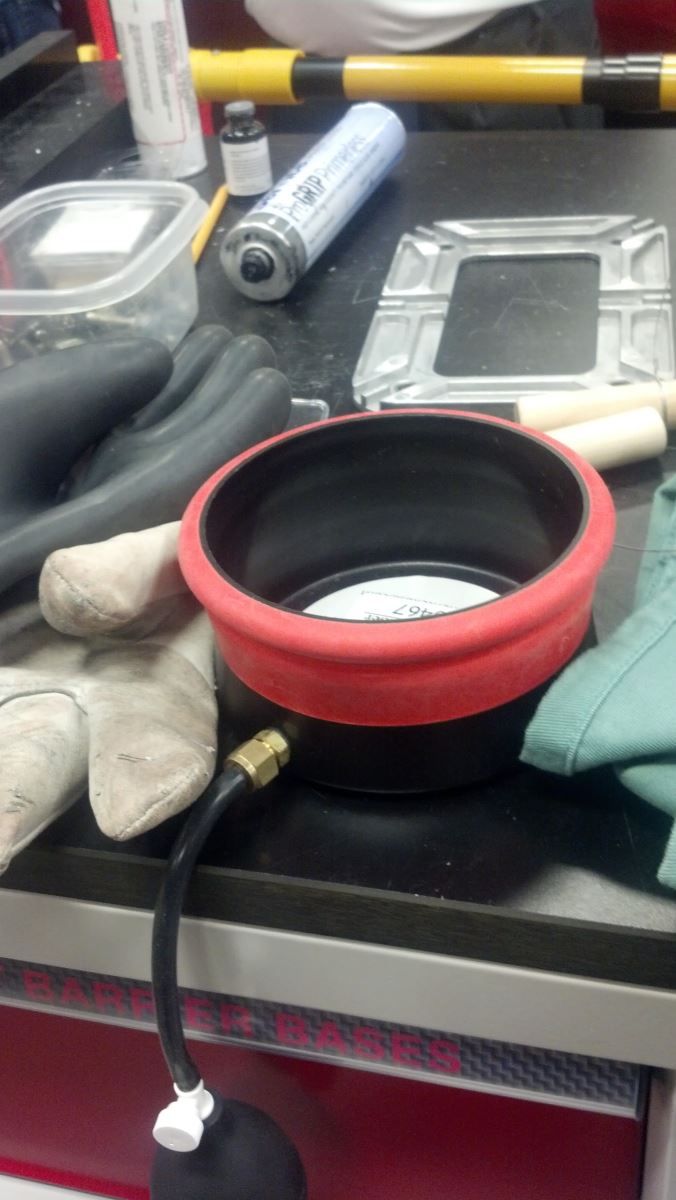 A red bowl is sitting on a table next to gloves | Autotrends