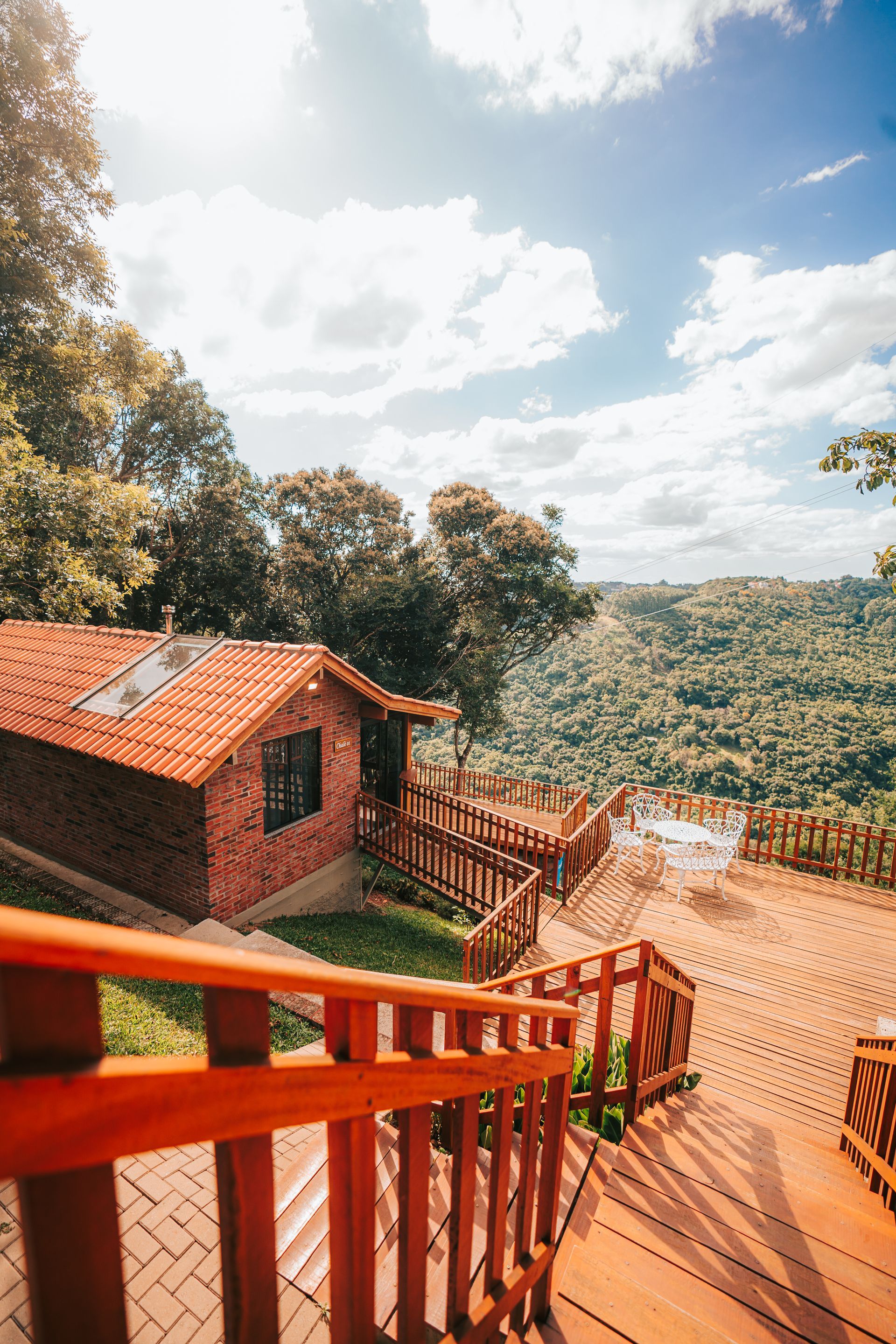 Casa moderna com piscina e painéis solares, cercada por árvores verdejantes, sob um céu azul brilhante.