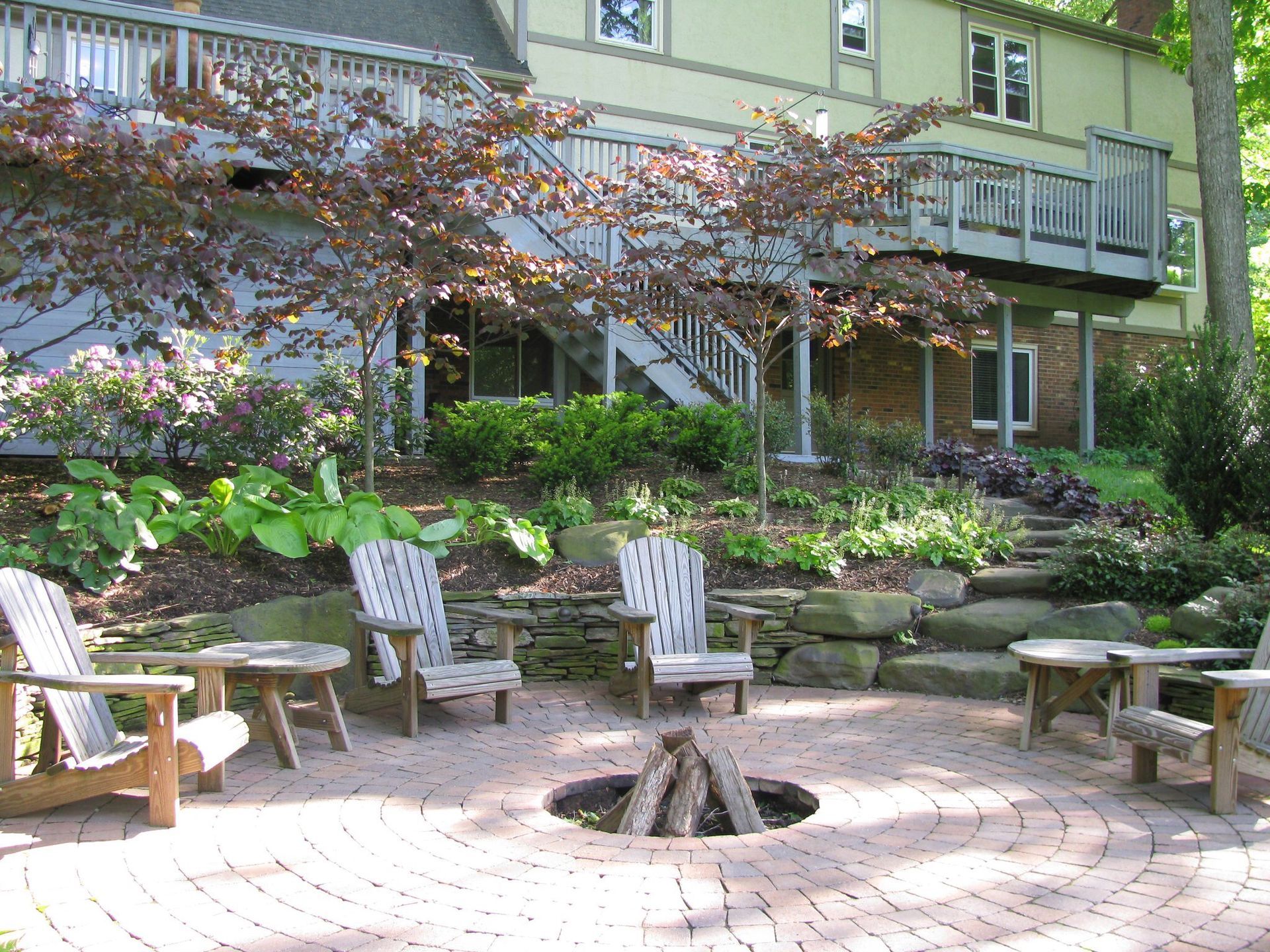 A fire pit surrounded by chairs and tables in front of a house